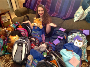 Eden Wallace is surrounded by backpacks she collected and stuffed for children entering foster care